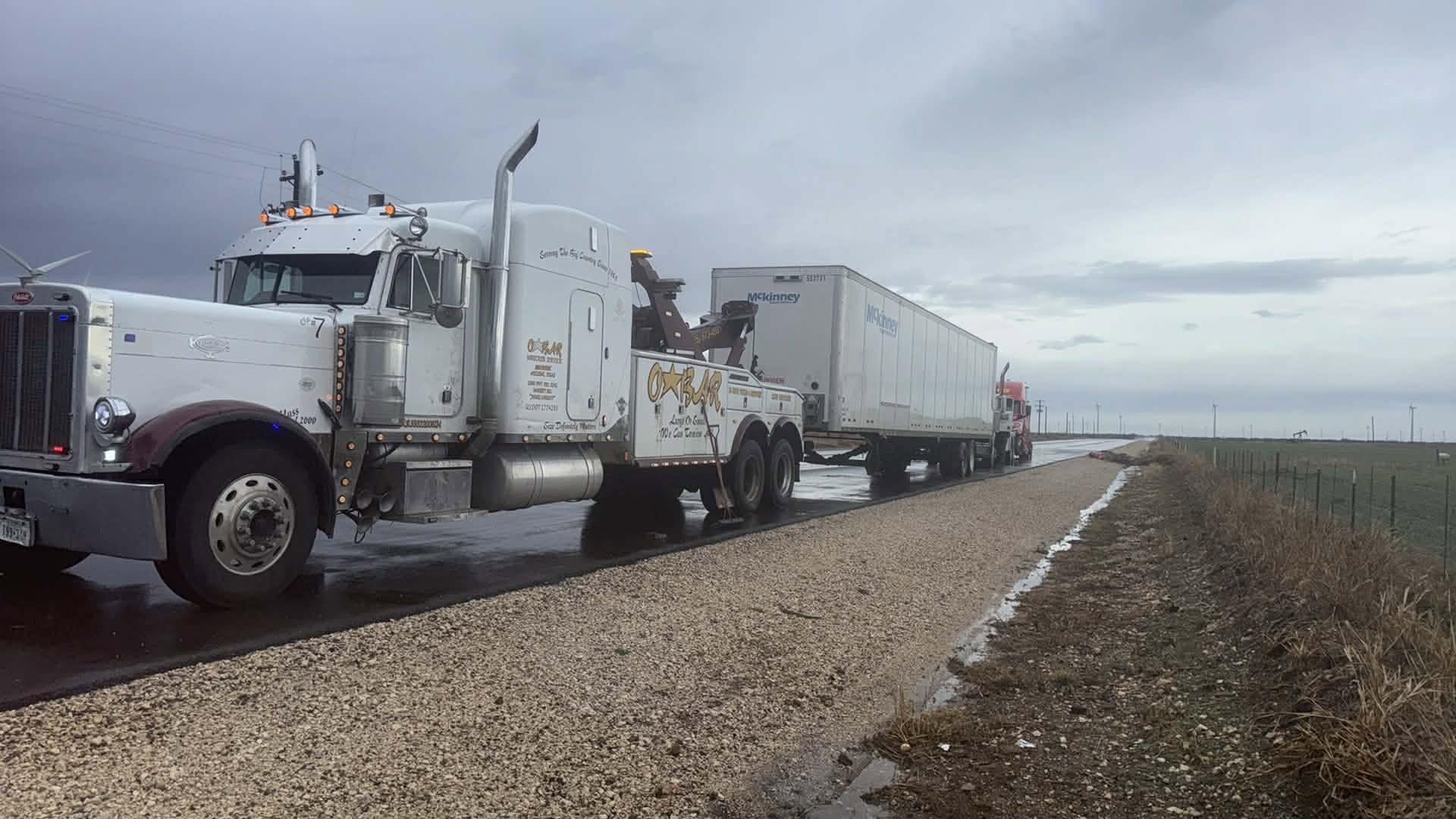 O'Bar wrecker towing a semi trailer on a roadside